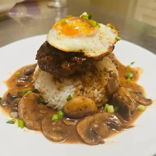 Red Ginger's Loco Moco with a fried egg, hamburger patty, rice, mushroom gravy, and scallions.